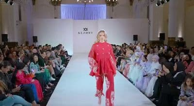 a woman walking down a runway in front of a crowd of people