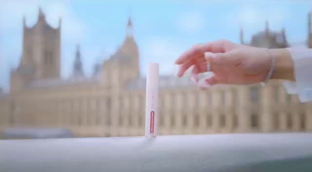 a person holding a small tube of toothpaste in front of a building