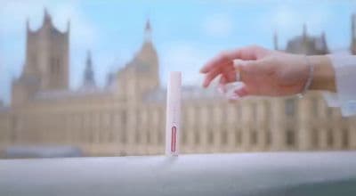 a person holding a small tube of toothpaste in front of a building