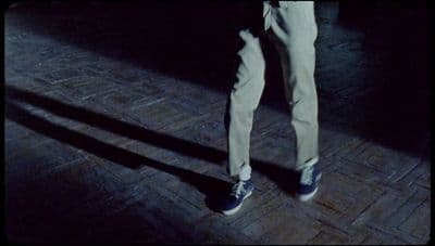 a person standing on a brick floor holding a cell phone