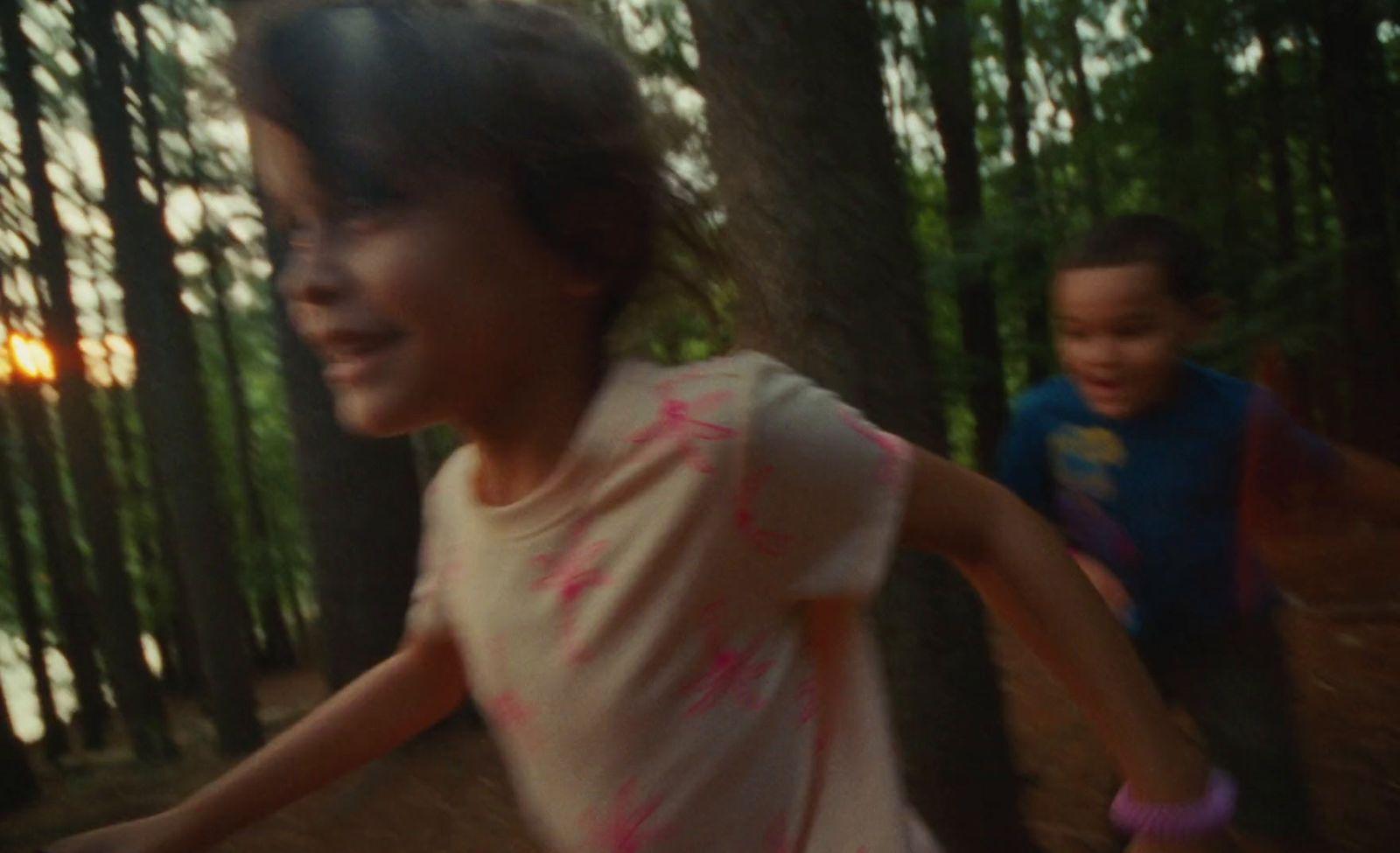 a couple of kids running through a forest