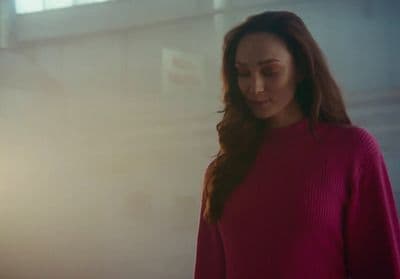 a woman in a red sweater looking down at her cell phone