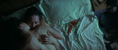 a shirtless man and woman laying in bed