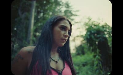 a woman with long black hair wearing a pink shirt