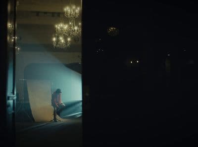 a woman sitting on a stool in a dark room