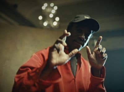 a man in a red shirt and hat making a peace sign