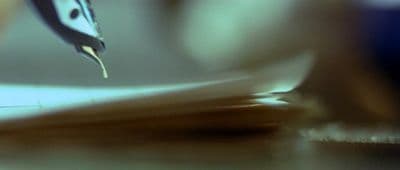 a close up of a person writing on a piece of paper