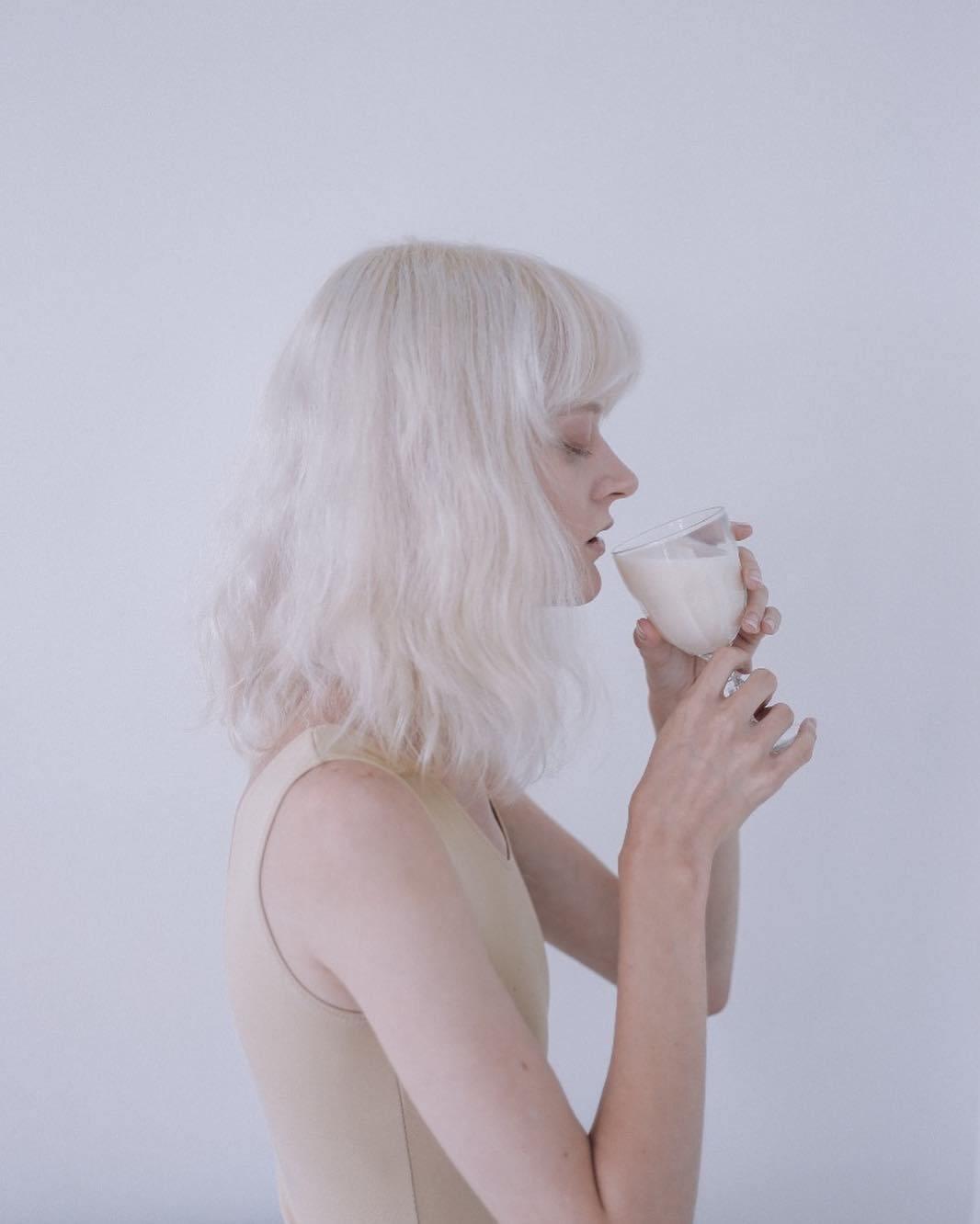 a woman with white hair holding a glass of milk
