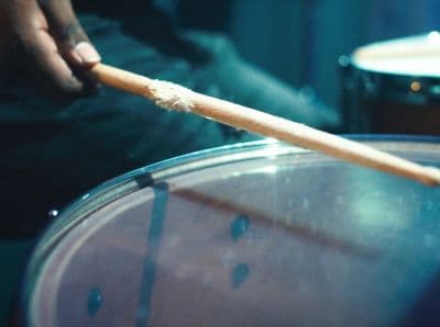 a person holding a wooden stick over a drum