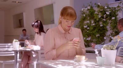 a woman sitting at a table using a cell phone