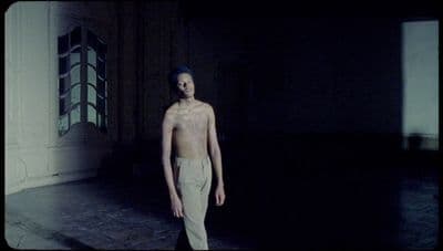 a man without a shirt standing in a dark room