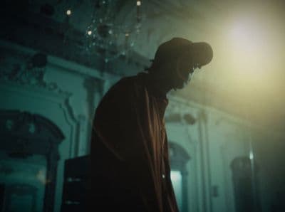 a man standing in a dark room with a hat on