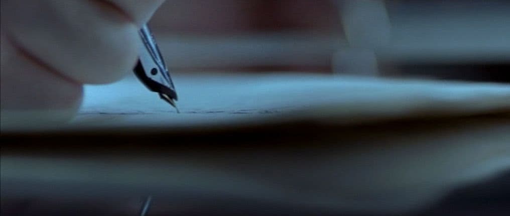 a person writing on a piece of paper with a pen