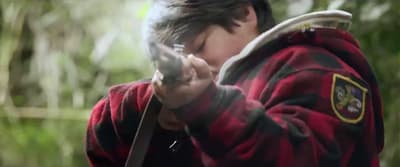 a boy in a red and black jacket holding a cell phone