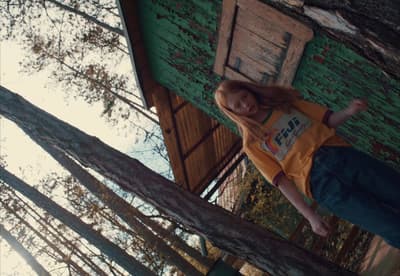 a girl standing on a tree branch in front of a building