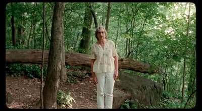 a woman standing in the middle of a forest