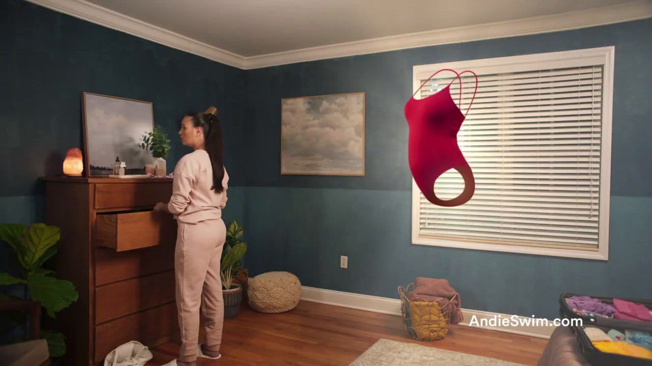 a woman standing in front of a dresser in a room