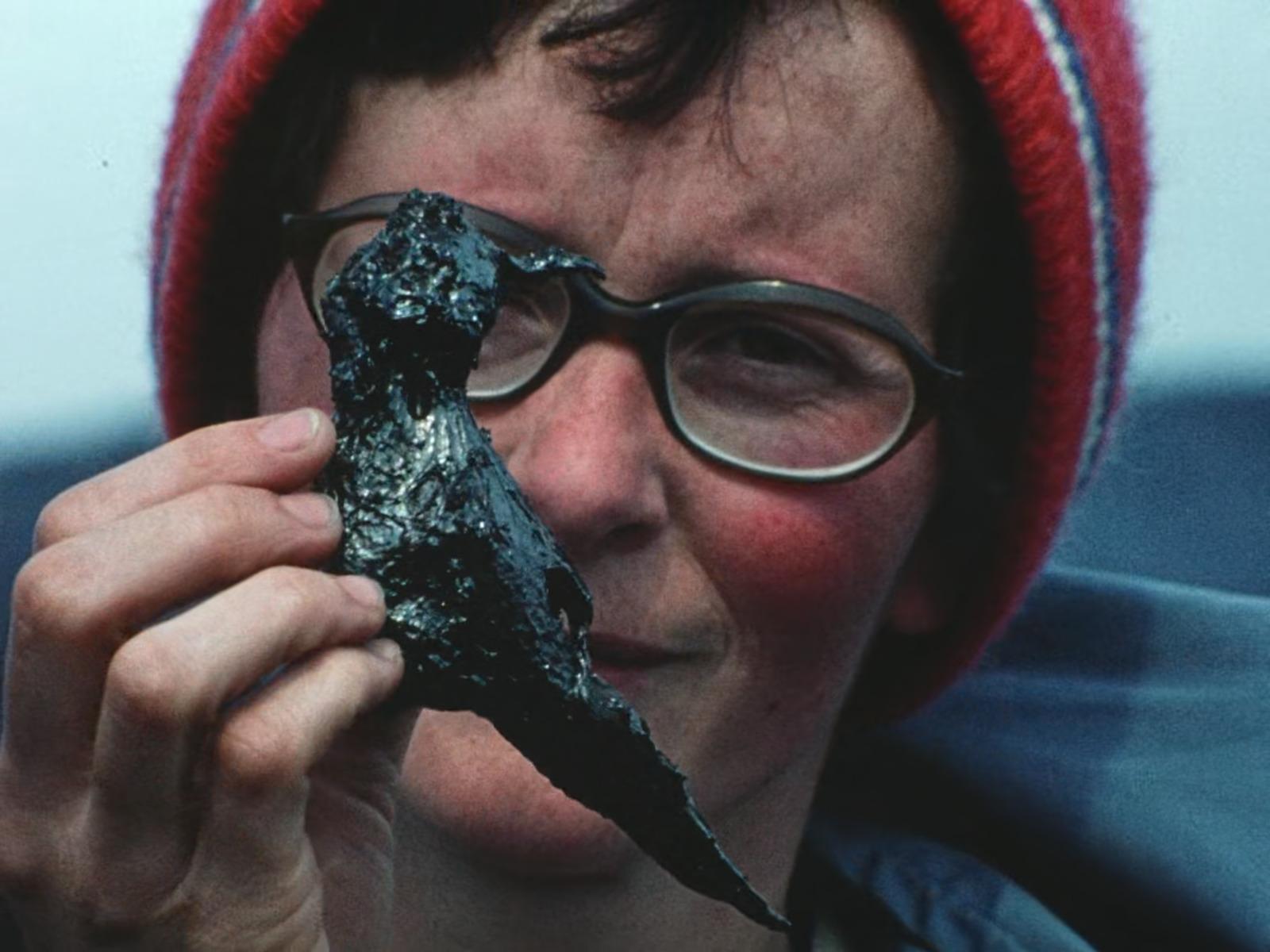a woman holding up a piece of black substance to her face