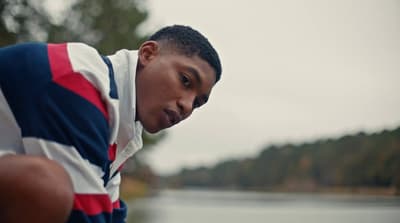 a man in a red, white and blue shirt looking down