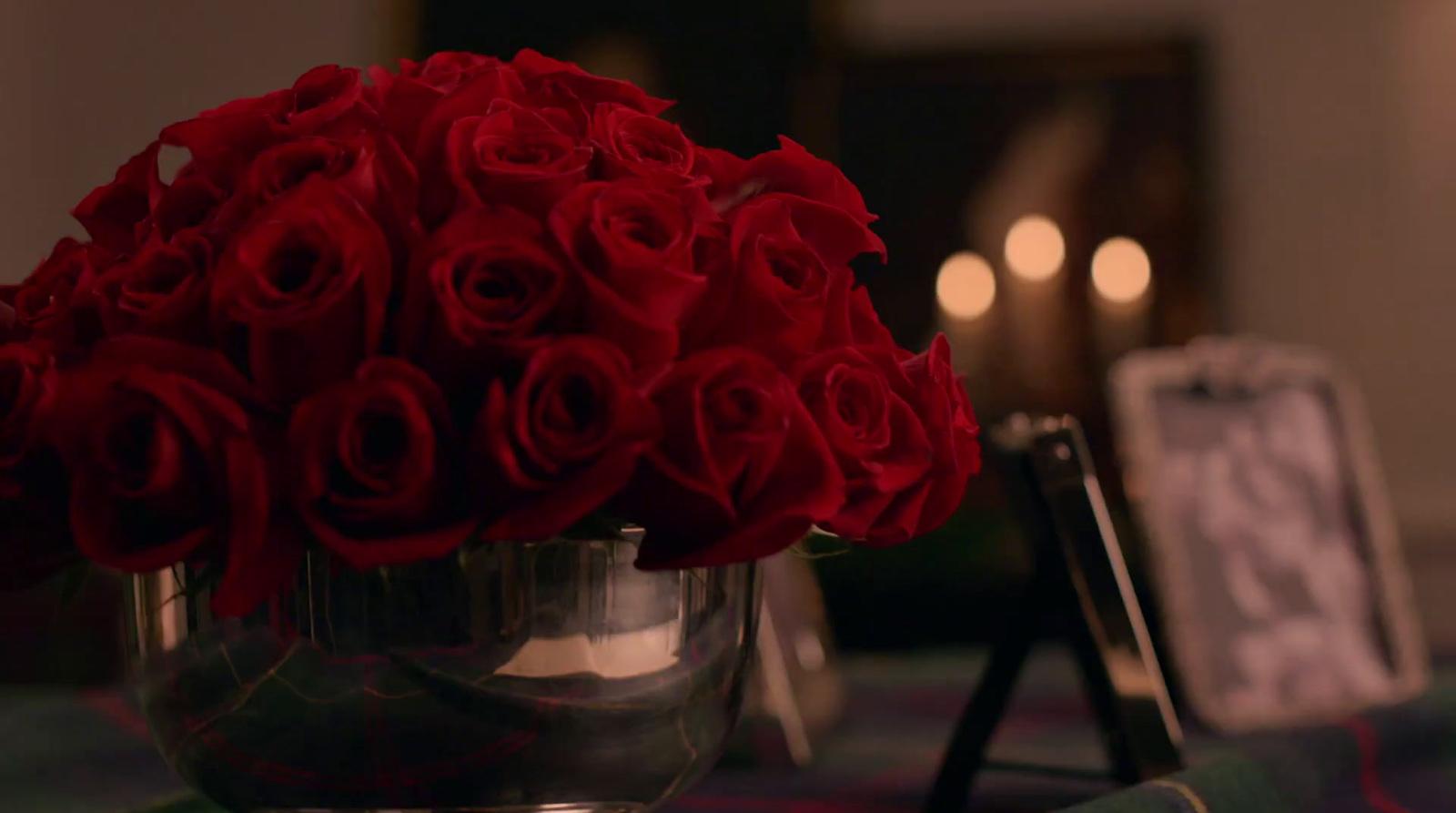 a bunch of red roses in a silver vase