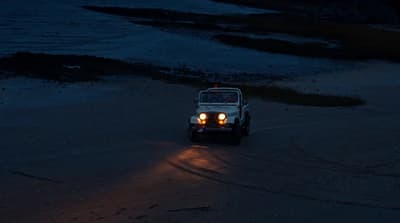 a jeep driving down a beach at night