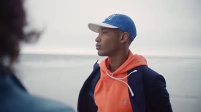 a man wearing a blue and orange jacket and a hat