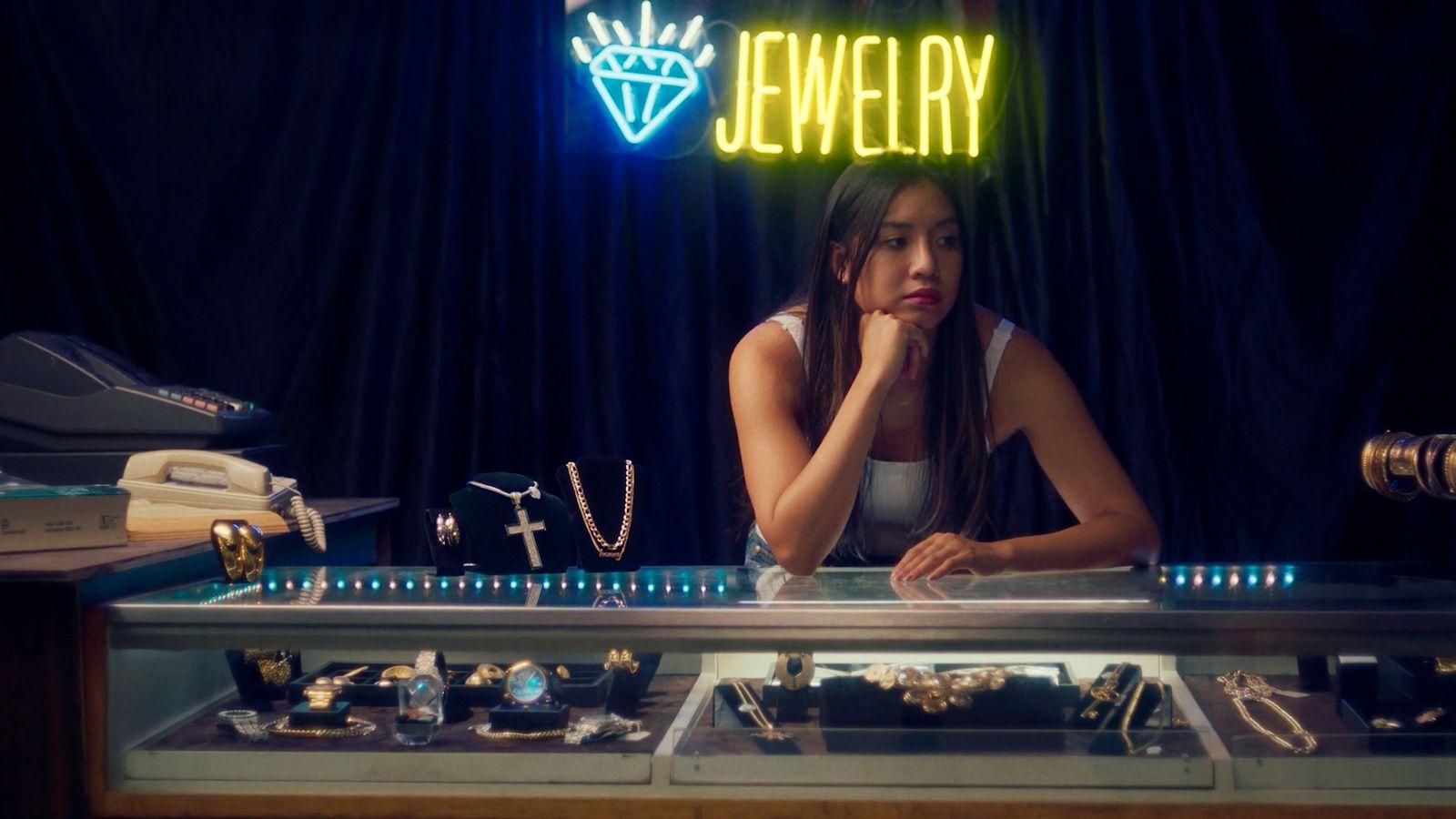a woman sitting in front of a jewelry display