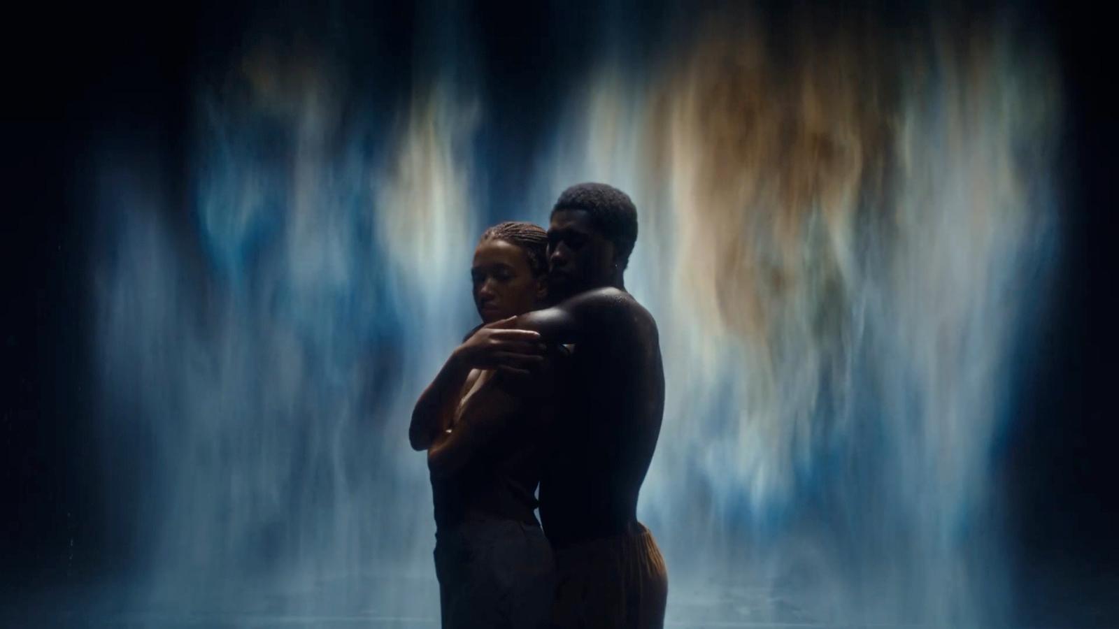 a man and a woman standing in front of a waterfall