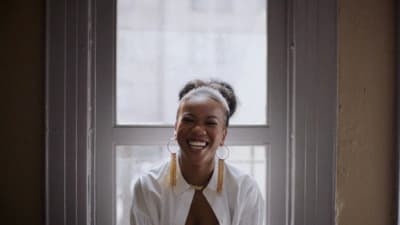 a smiling woman sitting in front of a window