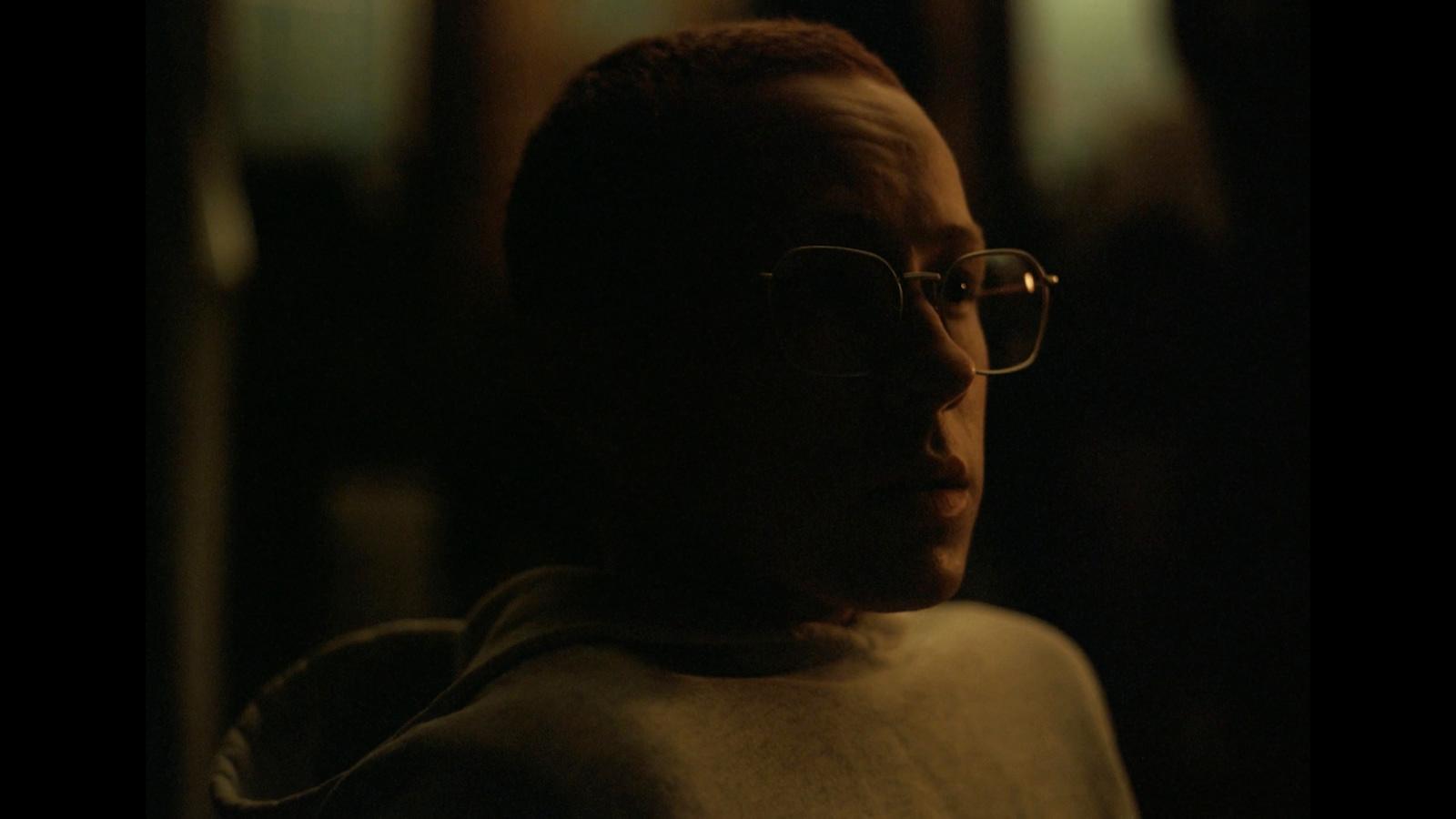 a man wearing glasses in a dark room