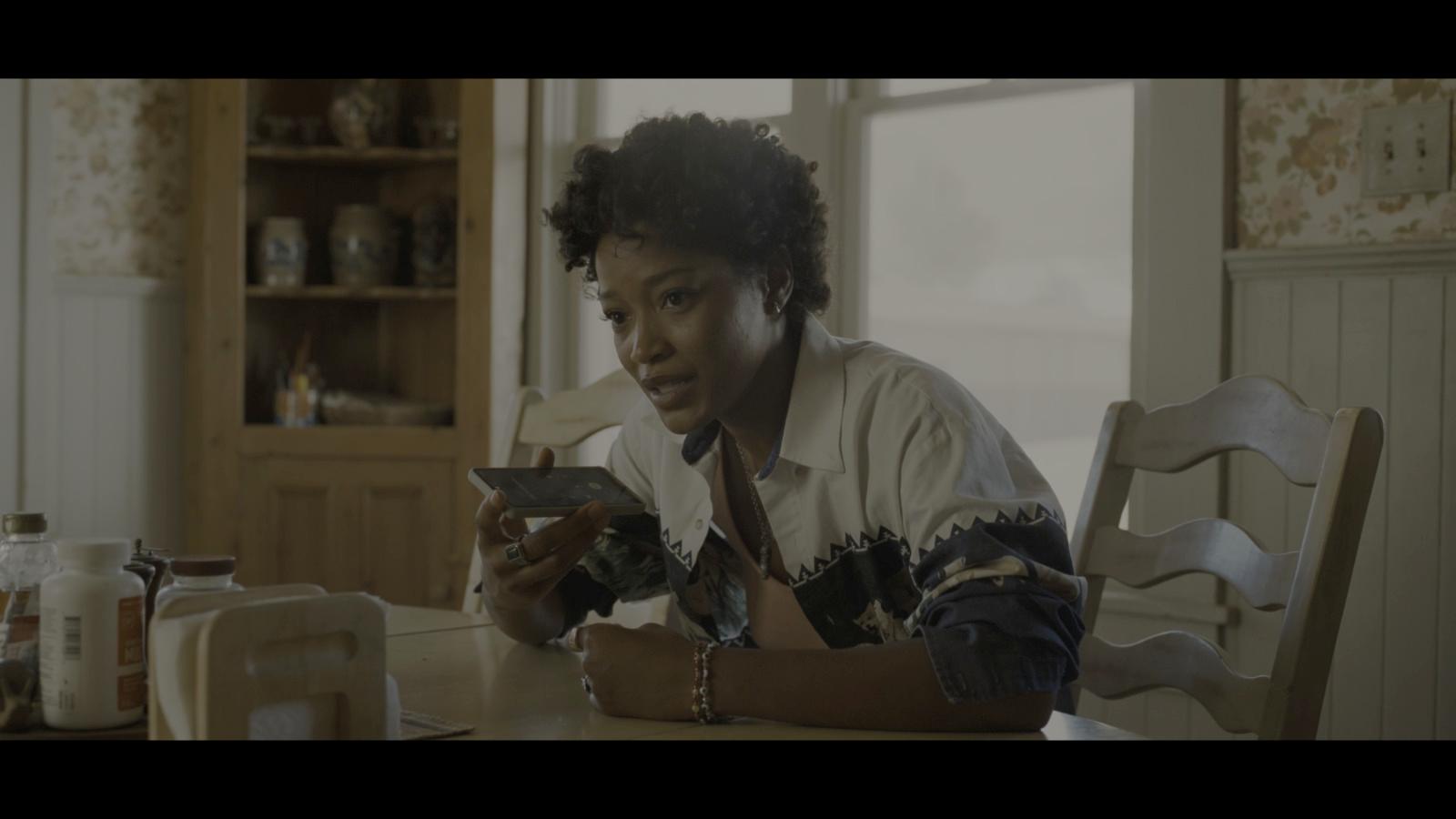a woman sitting at a table looking at a cell phone