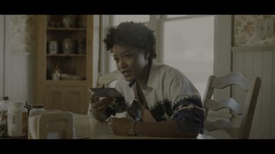a woman sitting at a table looking at a cell phone