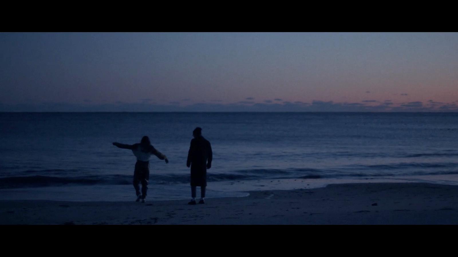 a couple of people standing on top of a beach