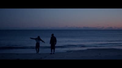 a couple of people standing on top of a beach