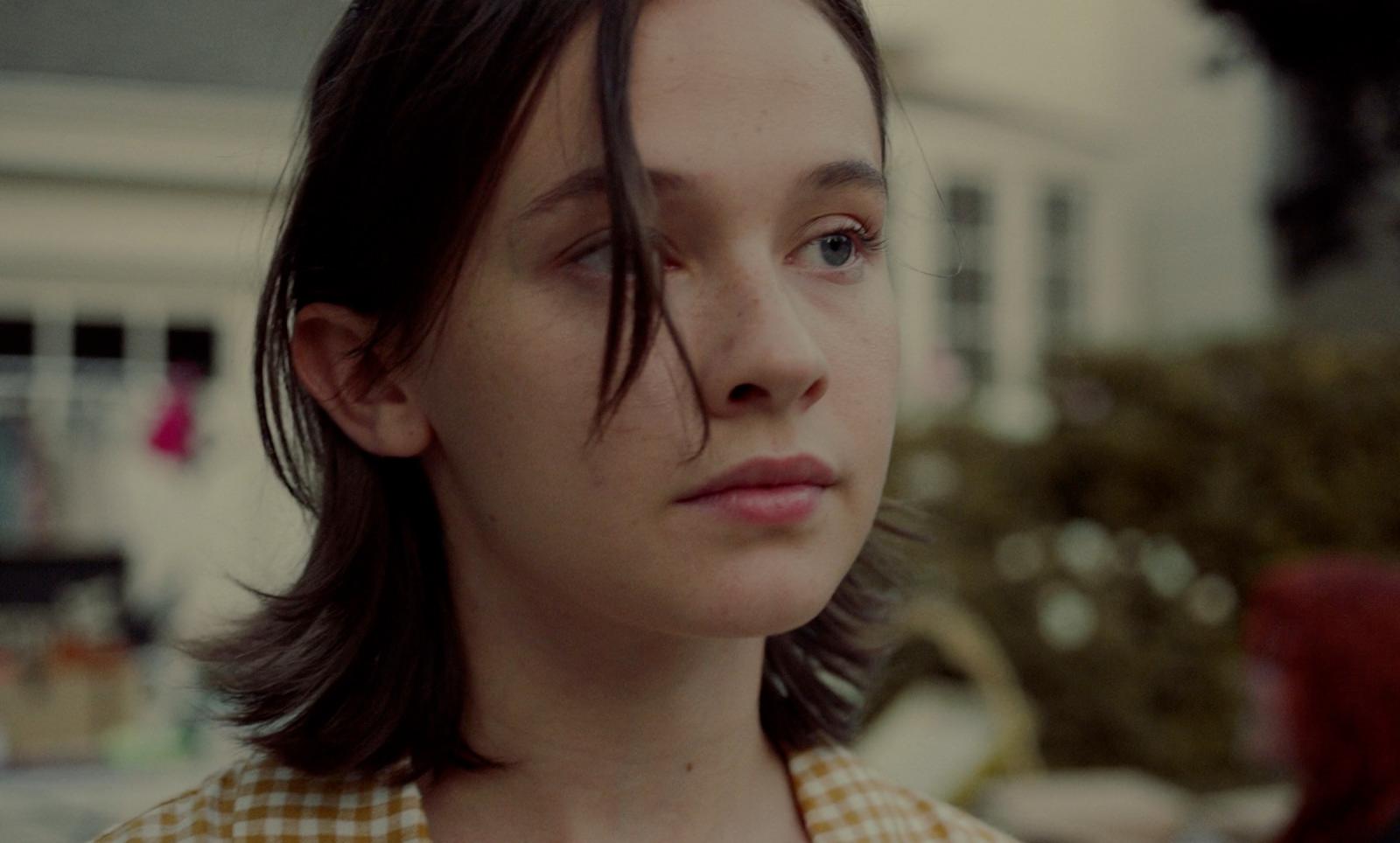 a close up of a person with a house in the background
