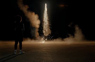 a person standing in the middle of a street watching fireworks