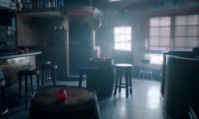 a dimly lit room with stools and a bar