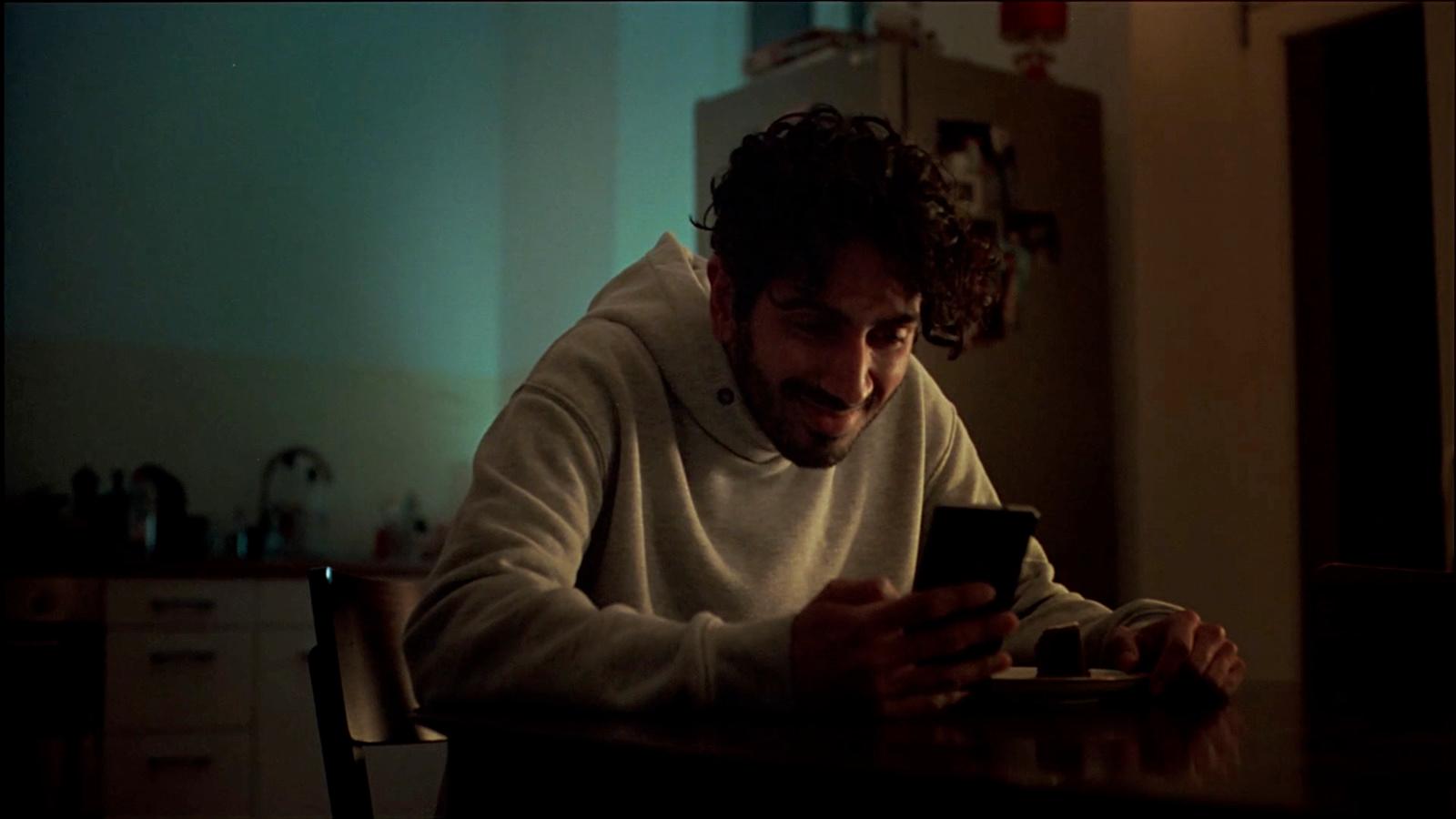 a man sitting at a table looking at a cell phone