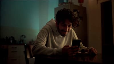 a man sitting at a table looking at a cell phone