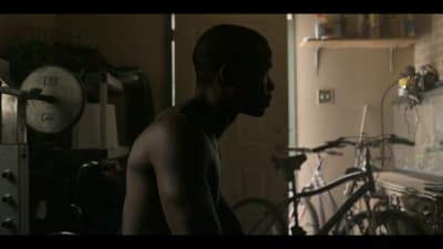 a shirtless man standing in a kitchen next to a bicycle