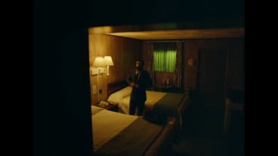 a man standing in a dark room next to two beds