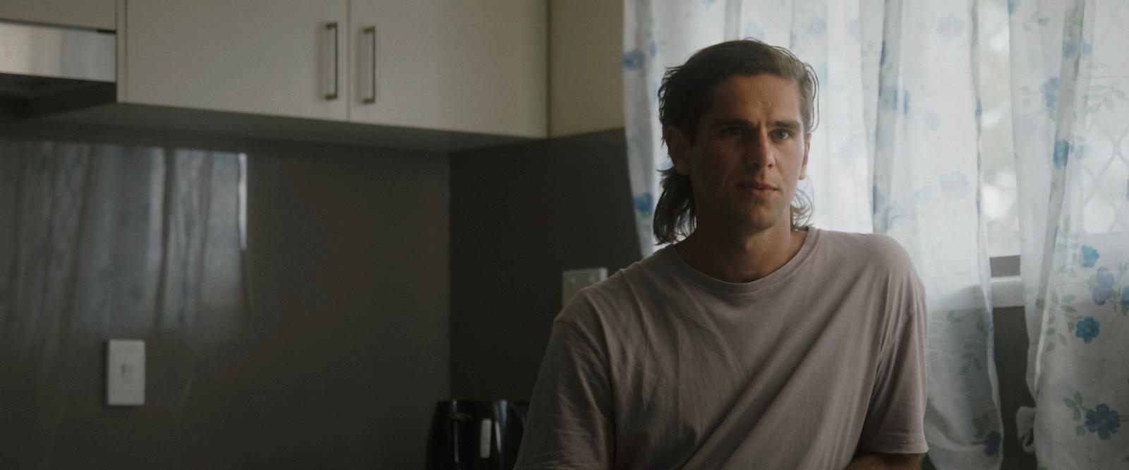 a man standing in a kitchen next to a window