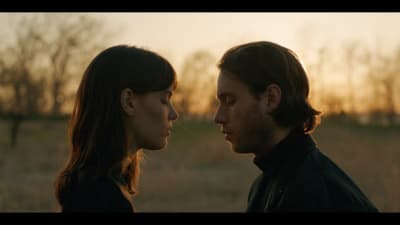 a man and a woman facing each other in a field