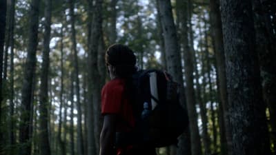a man with a backpack walking through a forest