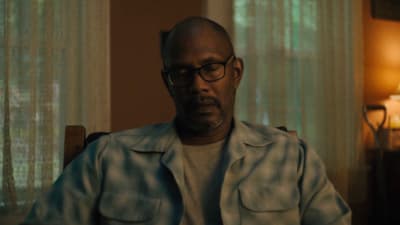 a man wearing glasses sitting in a chair
