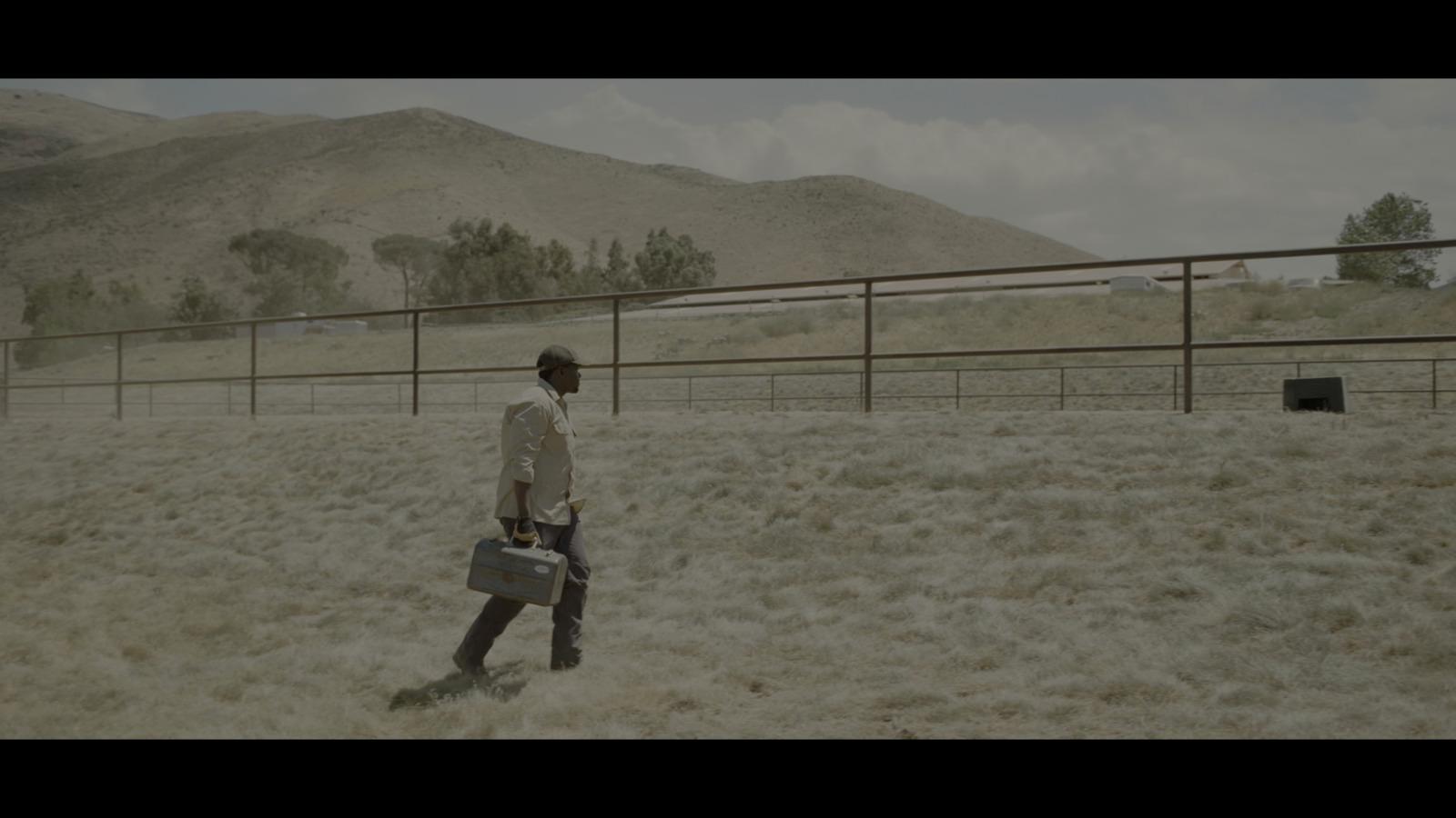 a man walking across a dry grass covered field