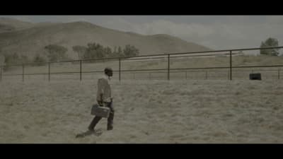 a man walking across a dry grass covered field