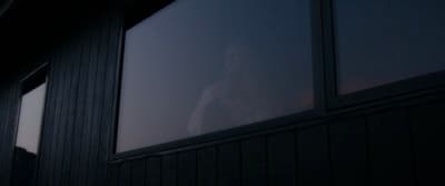 a woman standing outside of a window at night