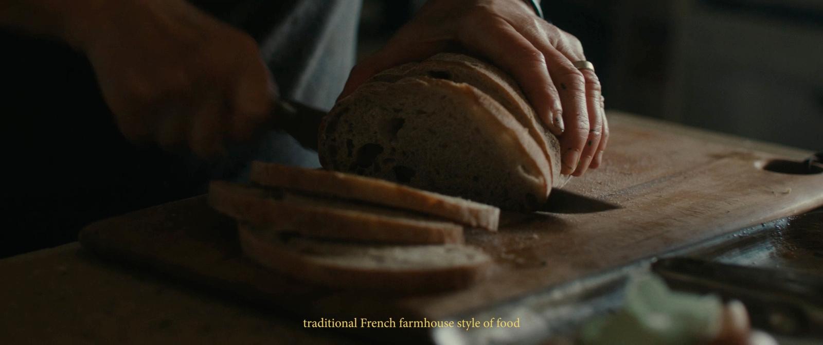 a person slicing a loaf of bread on a cutting board