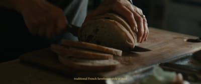 a person slicing a loaf of bread on a cutting board